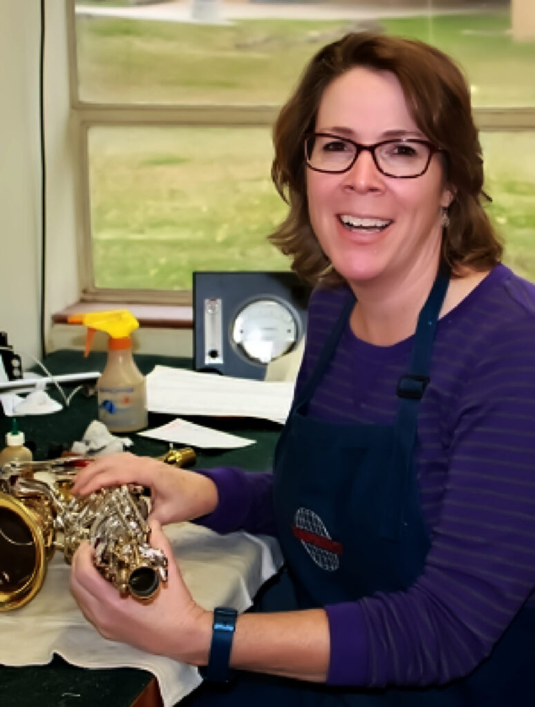 Ann MacMillan smiles at the camera holding an instrument.