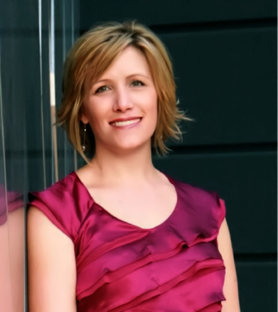 Rebecca Cordes smiles in a pink dress leaning against a reflective wall.